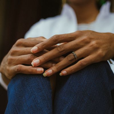 Hands folded in a relaxed position on a lap.